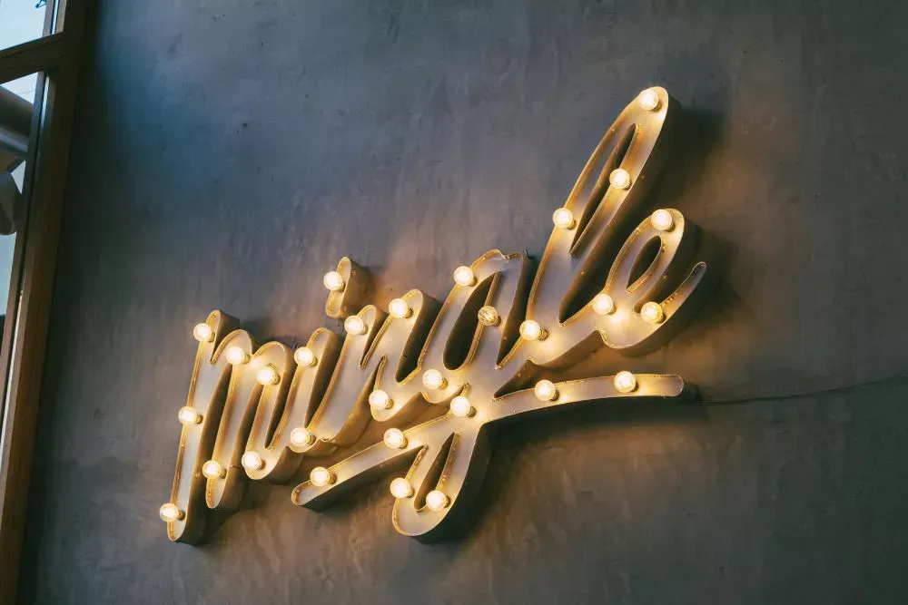 Illuminated custom wall sign with the word “Smile” mounted on an interior wall, used for decorative wall signage, branded office interiors, and modern business wall displays.