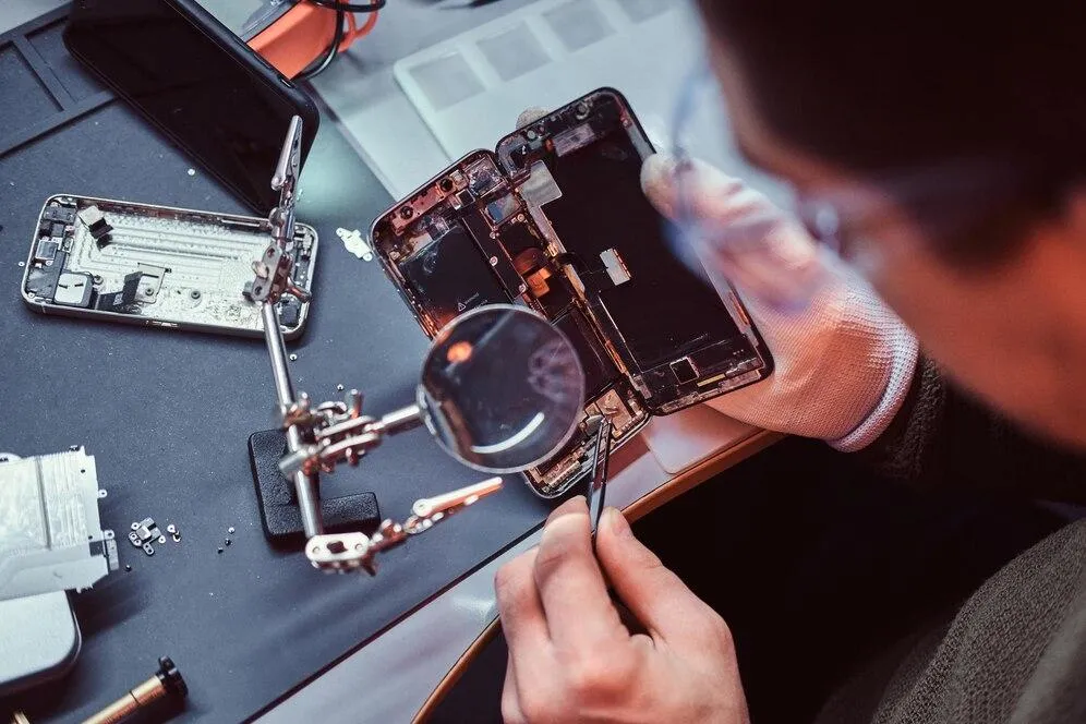 Technician repairing a smartphone battery and internal circuitry at Cellular Repair 1