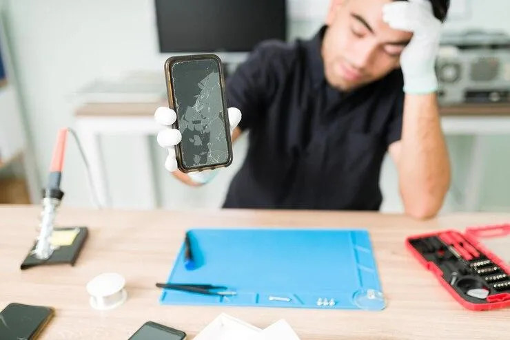 Technician inspecting a water-damaged smartphone during water damage restoration and repair at Cellular Repair 1