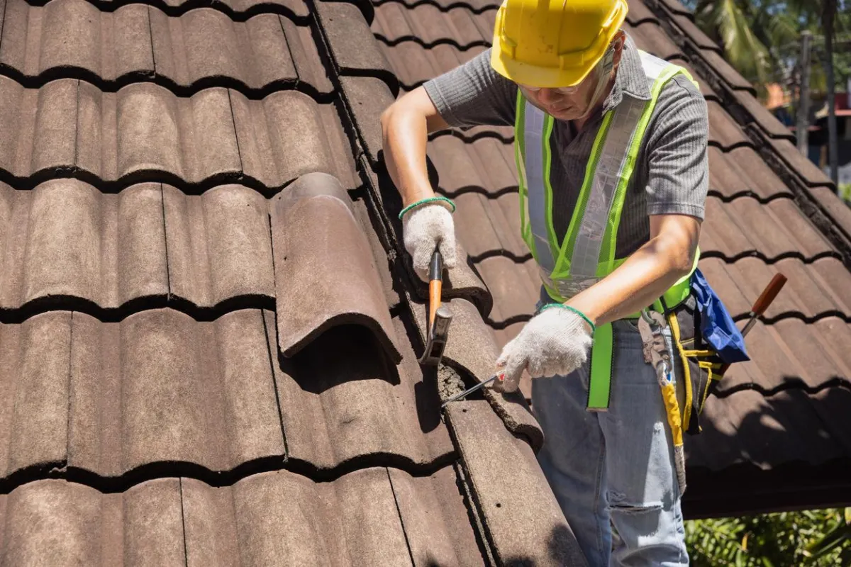 Roofer replacing tiles on a roof in Western NH, showcasing expert services by Olsen’s Roofing.