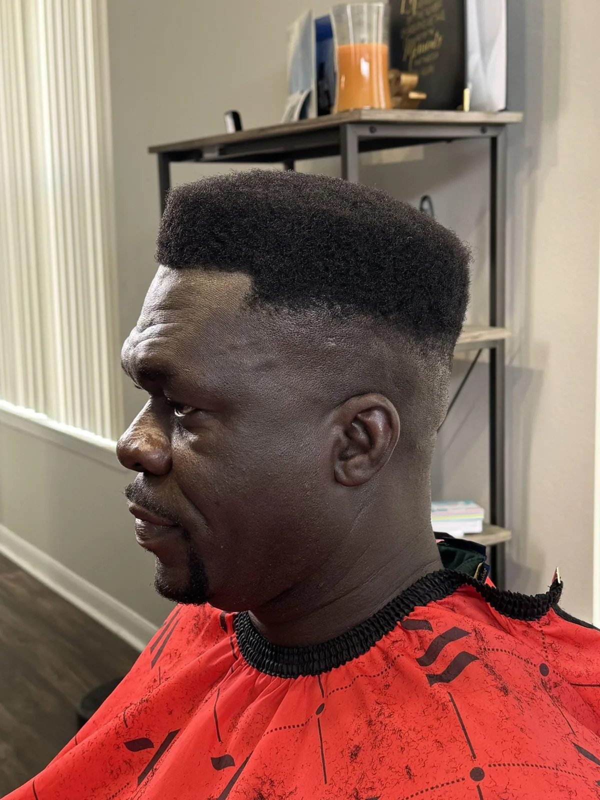 A skilled African American barber giving a clean fade to a Hispanic male client with dark hair, detailed focus on clippers and blend, warm natural lighting, modern barbershop décor with shelves and mirrors softly blurred, professional grooming atmosphere