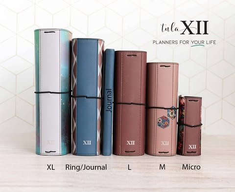 A flat lay of a modern desk with a pastel pink planner, gold pen, decorative washi tapes, and a cup of herbal tea. The items are neatly arranged on a white surface, with soft natural light highlighting the textures. The composition feels inviting and organized.