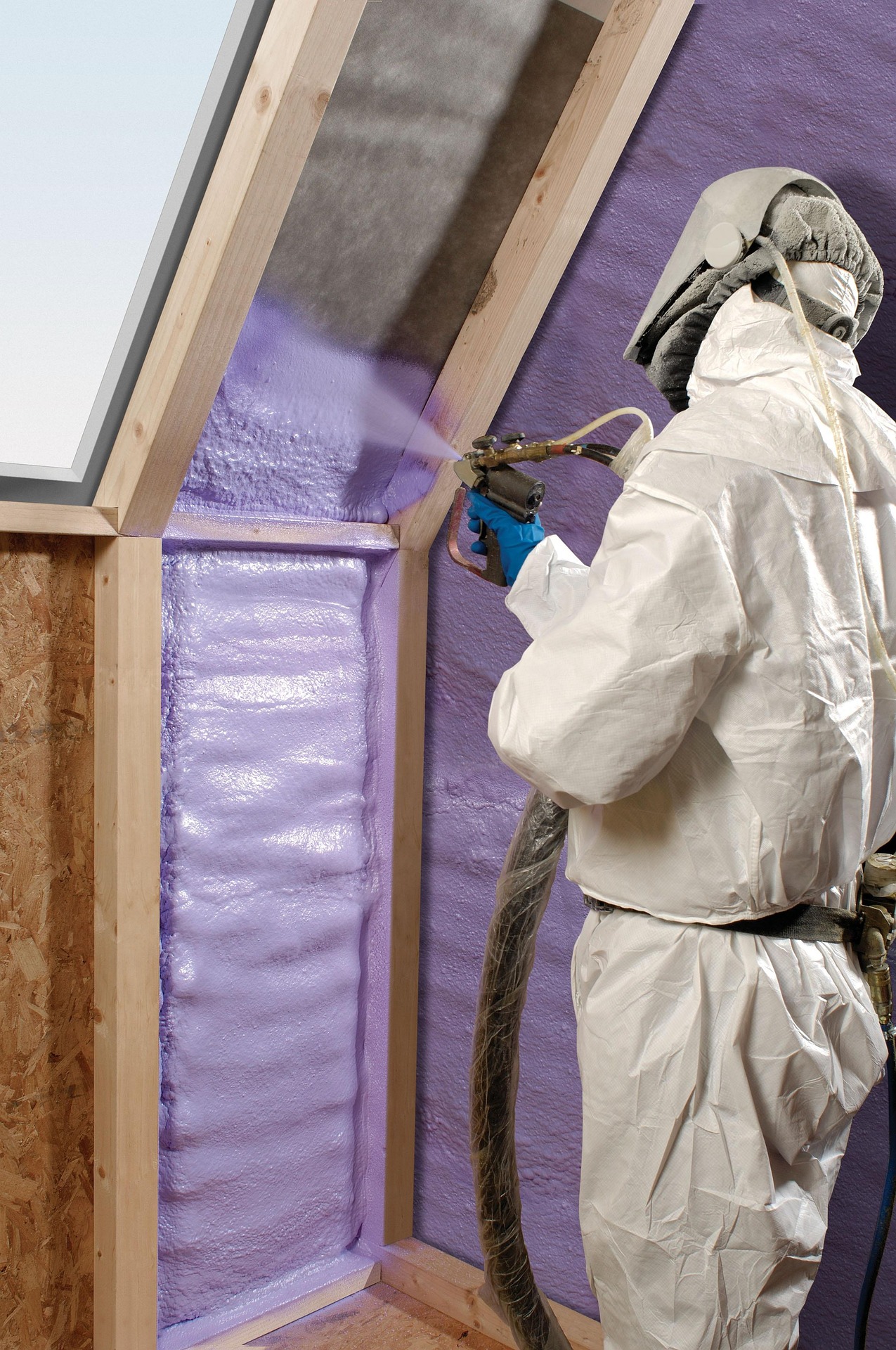 man spraying purple spray foam insulation on wall