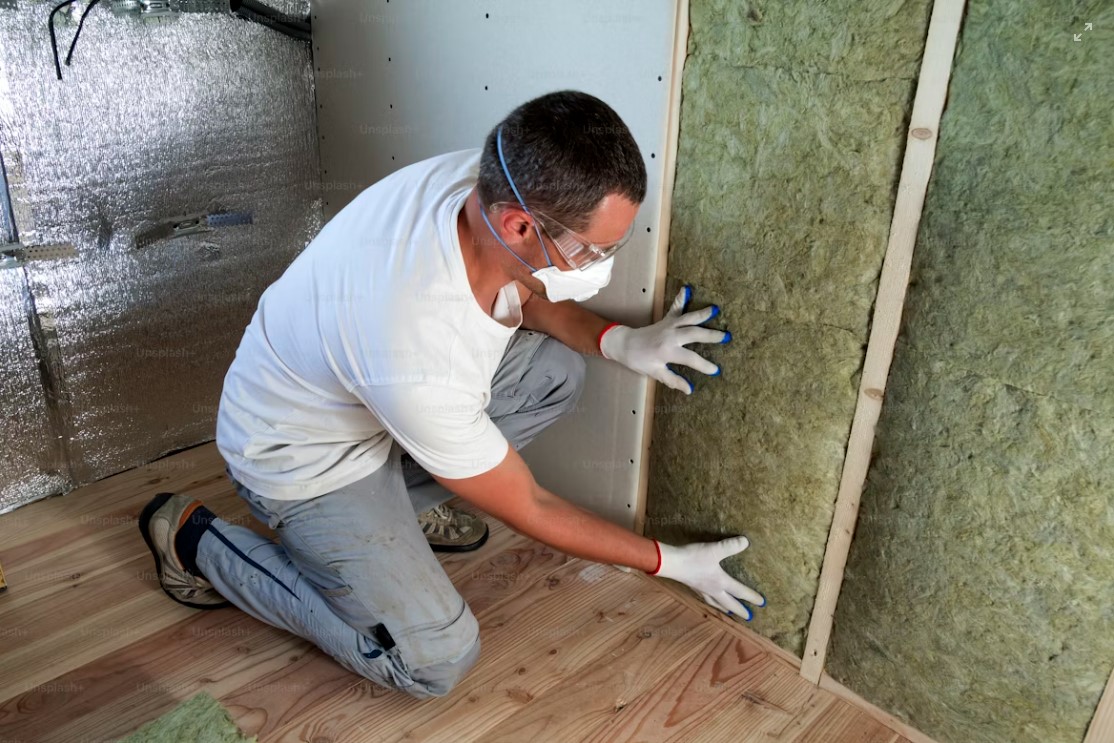 white shirt man installing rockwool insulation in wall