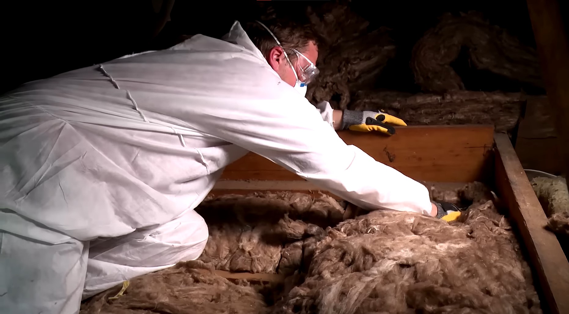 white man installing insulation onto bottom part of attic