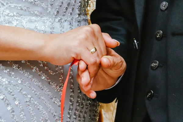 Couple’s hands tied with handfasting cords during a handfasting ceremony”