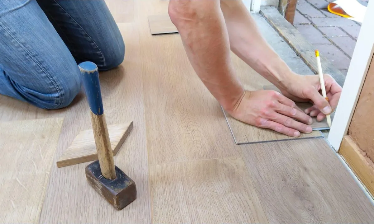 Worker measuring wooden flooring during commercial renovation, ensuring accuracy and quality installation.