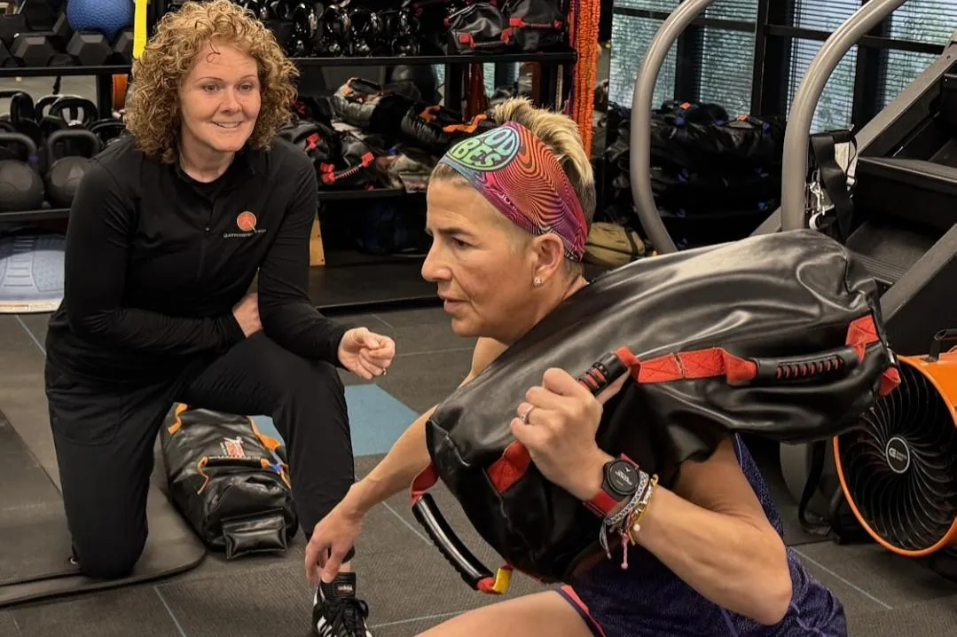 Personal trainer coaching an adult over 40 through a functional strength exercise at Quinntessential Fitness.