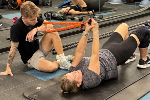 Adult over 40 performing a guided strength and mobility exercise with a fitness coach at Quinntessential Fitness.