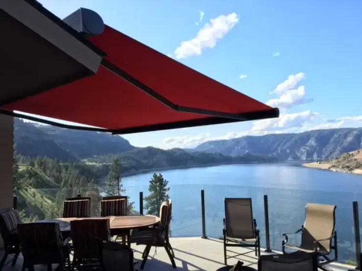 Custom red retractable awning installation on a residential deck overlooking a scenic landscape in Irvine, CA.