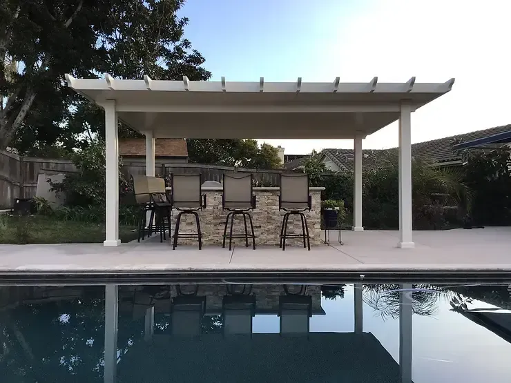 Freestanding white patio cover providing shade for an outdoor kitchen and bar next to a swimming pool in Brea, CA