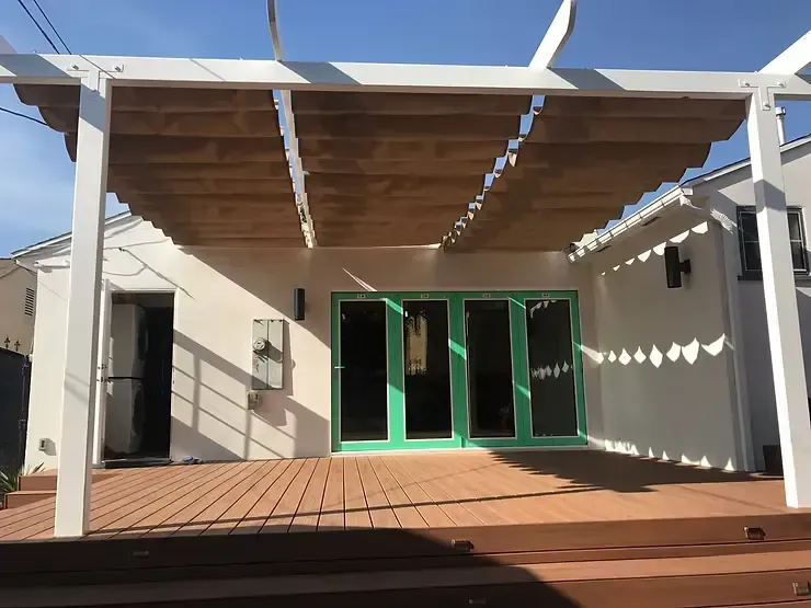 Tan slide-on-wire retractable canopy installed on a white pergola structure over a backyard deck in Villa Park, CA