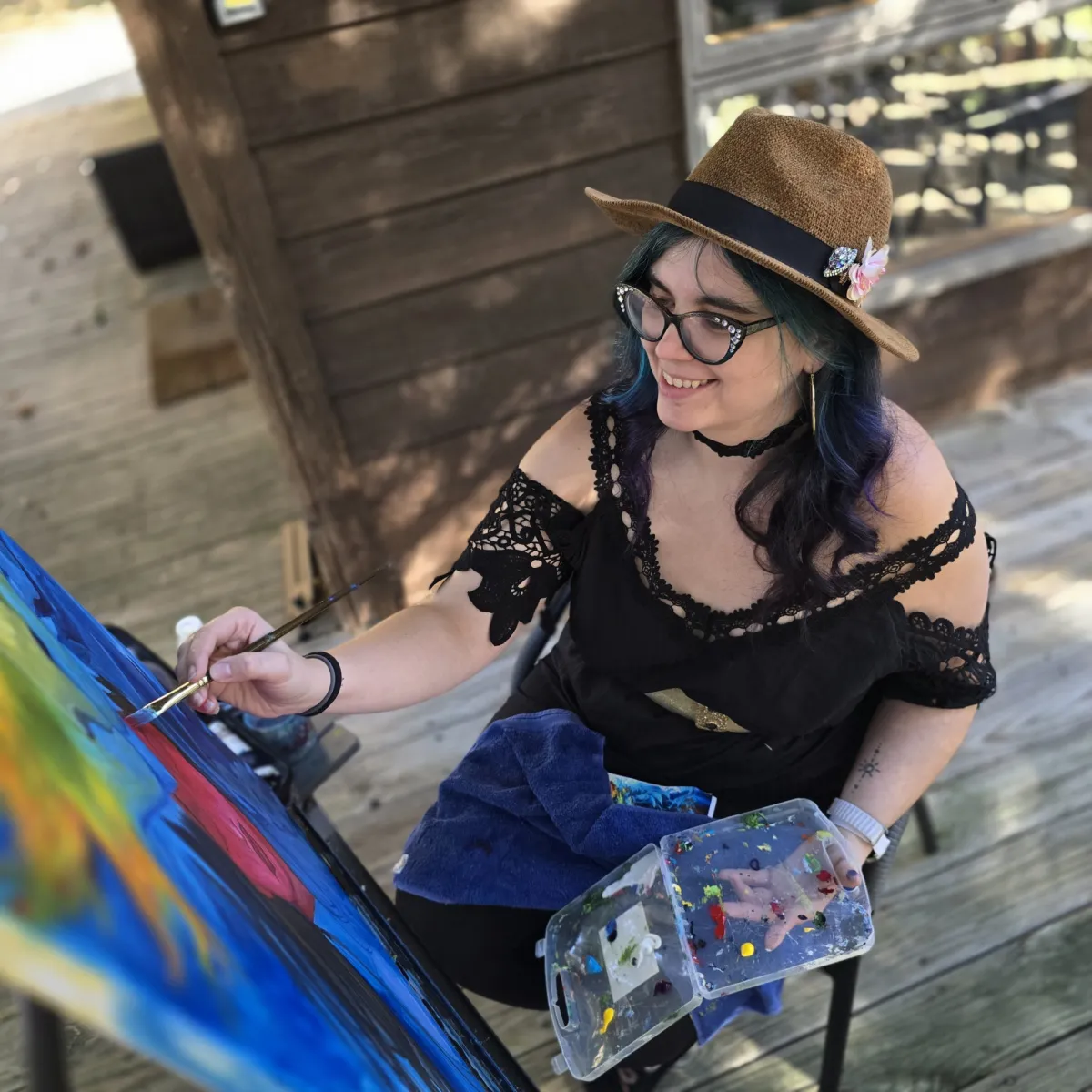 Artist Shannon Shine smiling in a cozy studio surrounded by art prints and paints