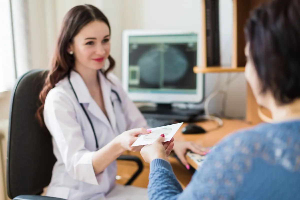 Doctor handing a patient a CD of their echocardiogram images and report.
