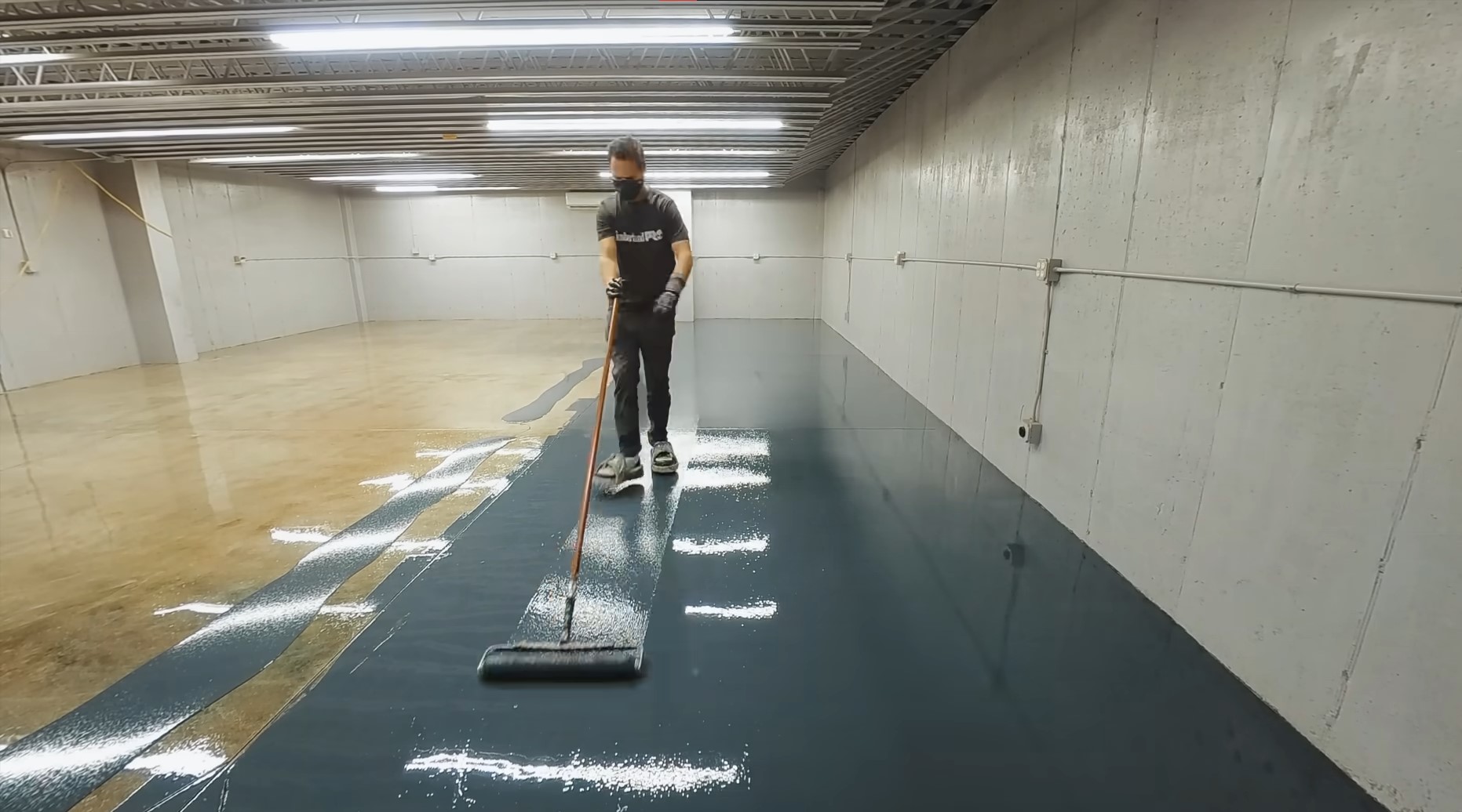 person coating warehouse floor a dark green and grey plain epoxy