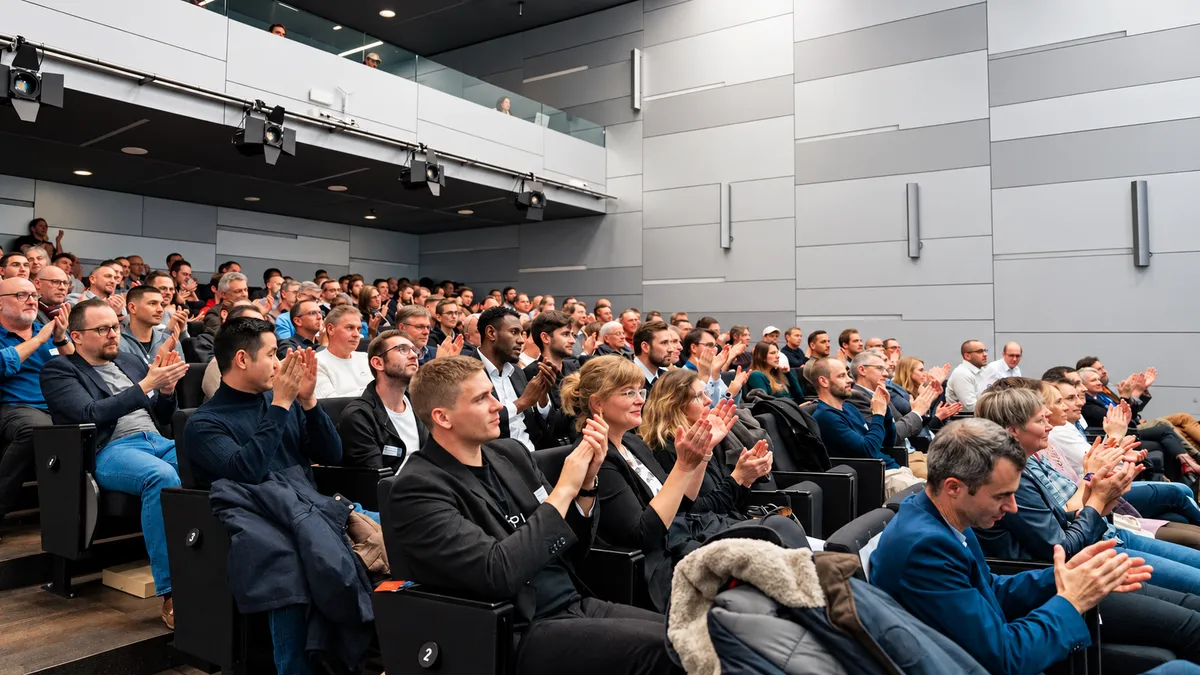 The audience at an AI Swiss conference applauds.