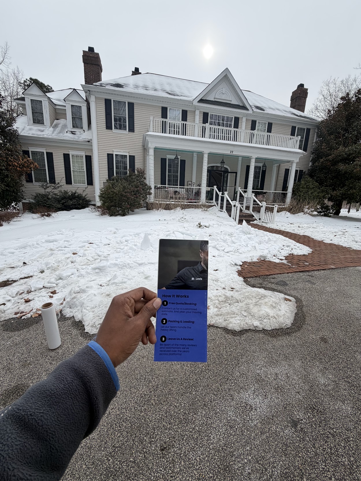 Luxury mansion moving services brochure held in front of a large snowy estate
