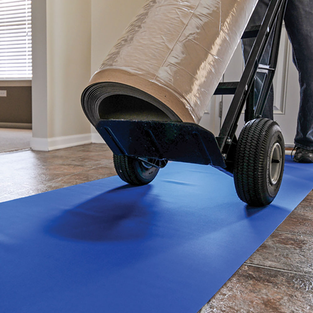 Professional movers using blue floor protection runners and a hand truck to prevent property damage