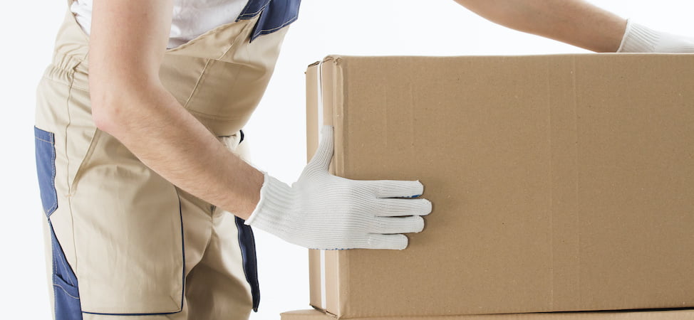 Professional mover wearing white safety gloves handling a cardboard moving box for delicate items