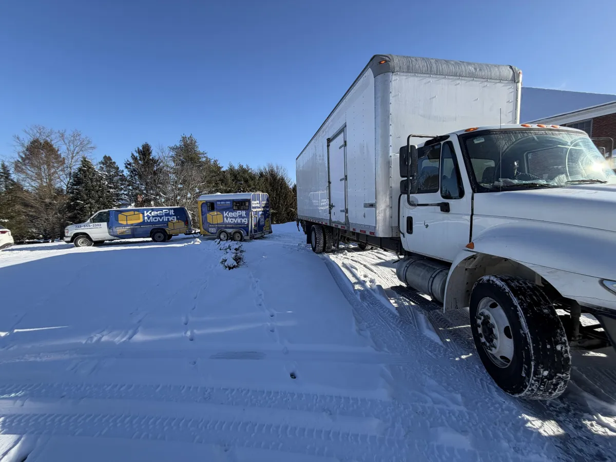 Dedicated moving truck and support vehicles prepared for a long-distance household relocation during winter conditions.