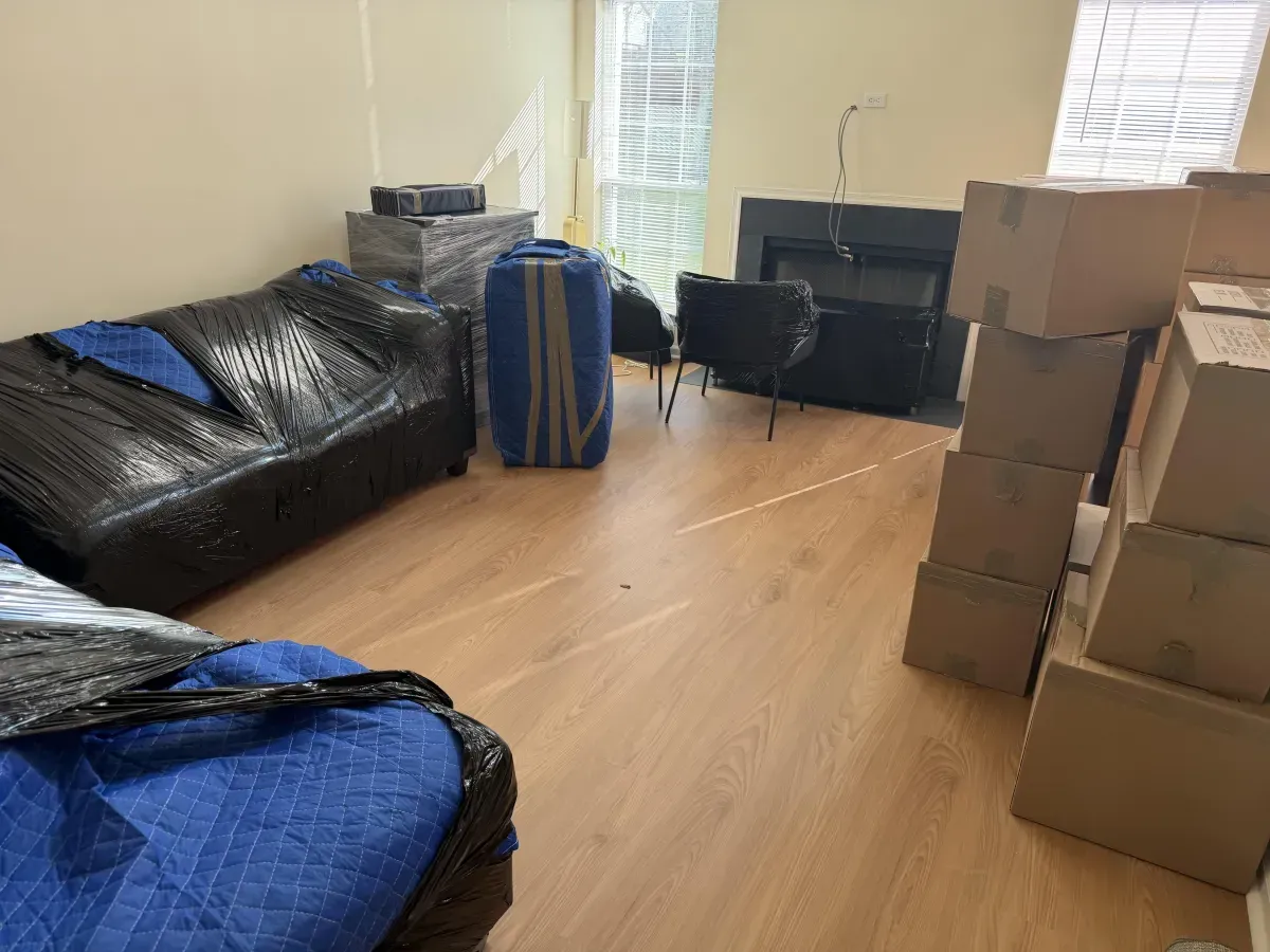 Living room with wrapped furniture and stacked moving boxes after a Burlington County move — Keep It Moving Services
