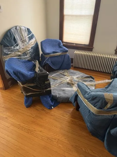 Living room with four armchairs wrapped in blue moving blankets — professional residential move in Franklin Township NJ by Keep It Moving Services