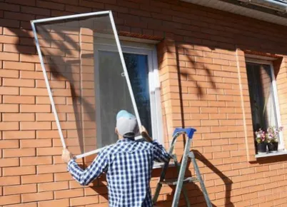 Worker on a lift outside of a building removing windows and placing plastic over removed openings.