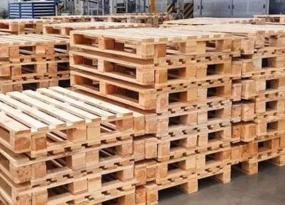 Two large trucks angled from he rear, each with a very large load of hundreds of wooden pallets.
