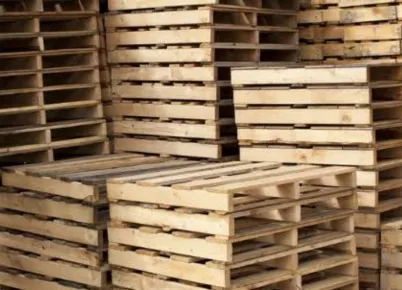 Two large trucks angled from he rear, each with a very large load of hundreds of wooden pallets.