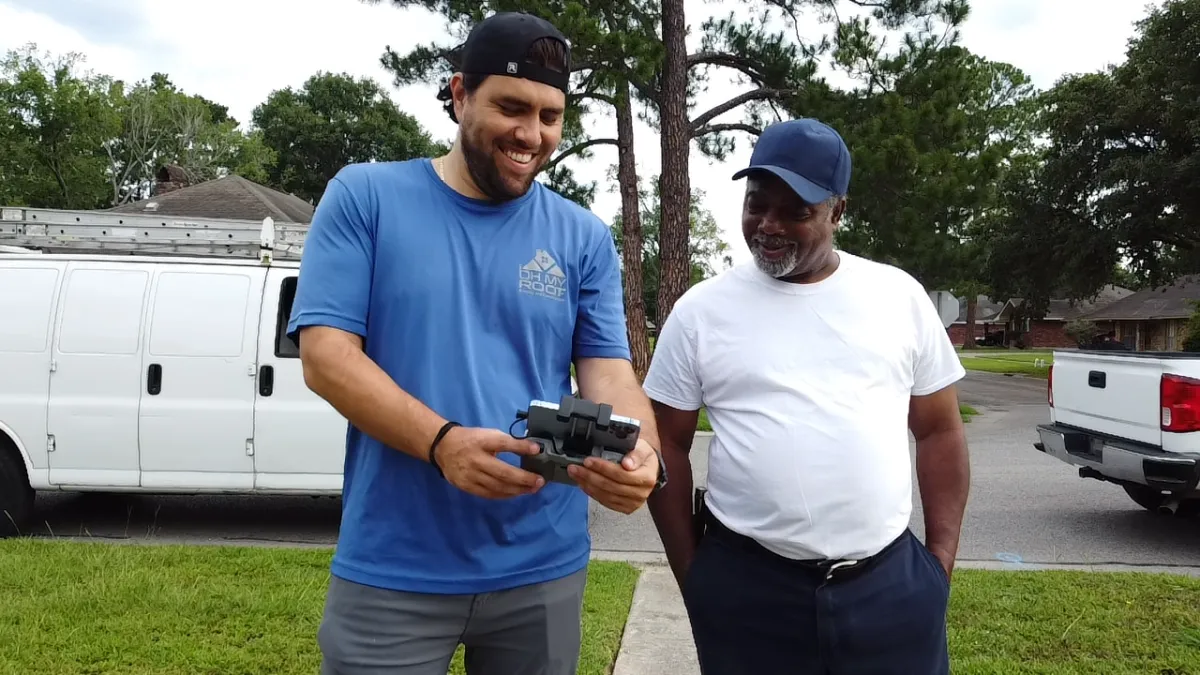 Two women in hard hats review blueprints indoors.