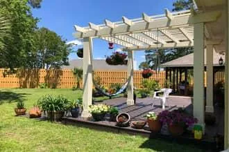 White wood pergola attached to home and covers deck 