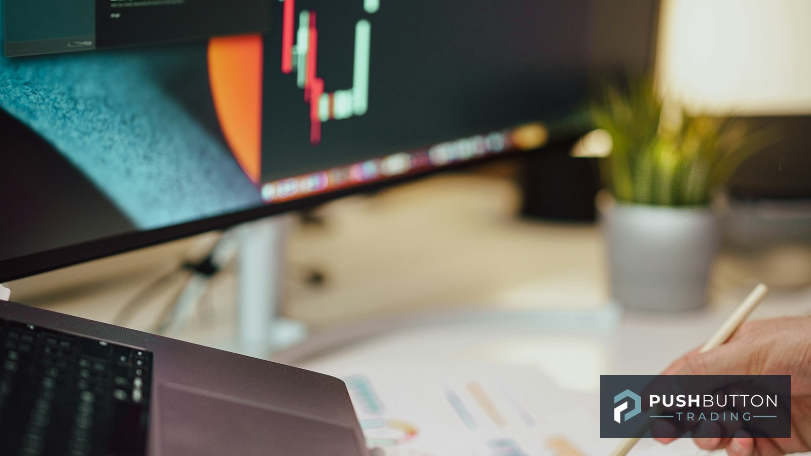 Trader reviewing a NinjaTrader 8 candlestick chart on a monitor beside a laptop and setup checklist notes, Push Button Trading logo overlay