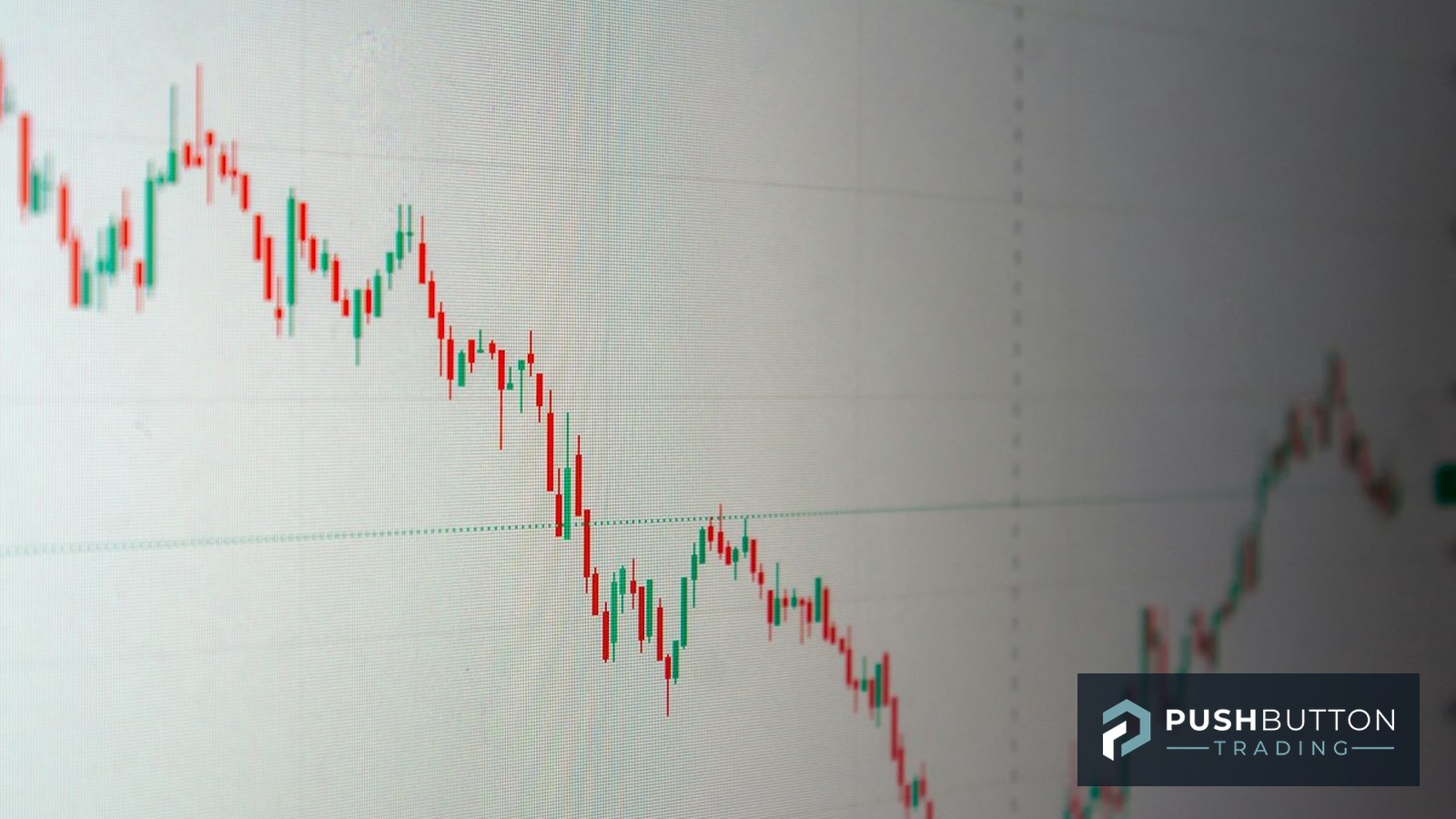 Angled monitor showing a candlestick trading chart in a sharp downtrend, Push Button Trading logo overlay