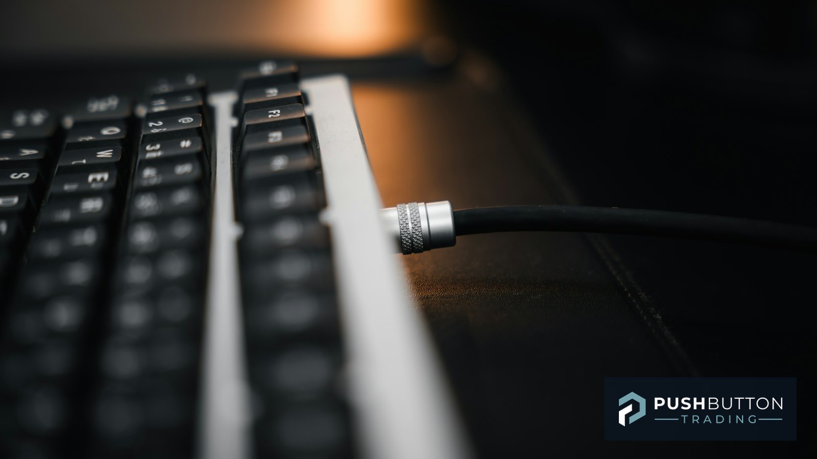 Close-up of a cable connecting into a computer keyboard, representing a NinjaTrader data feed and broker connection setup