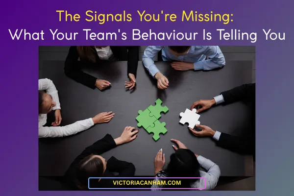 Victoria Canham Consultancy |  A high-angle, close-up shot of six people in business attire sitting around a dark boardroom table, their hands reaching towards two green puzzle pieces being fitted together in the centre. One person is holding a separate white puzzle piece. The image visually represents team collaboration, problem-solving, and missing pieces of information. The title text reads: "The Signals You're Missing: What Your Team's Behaviour Is Telling You."