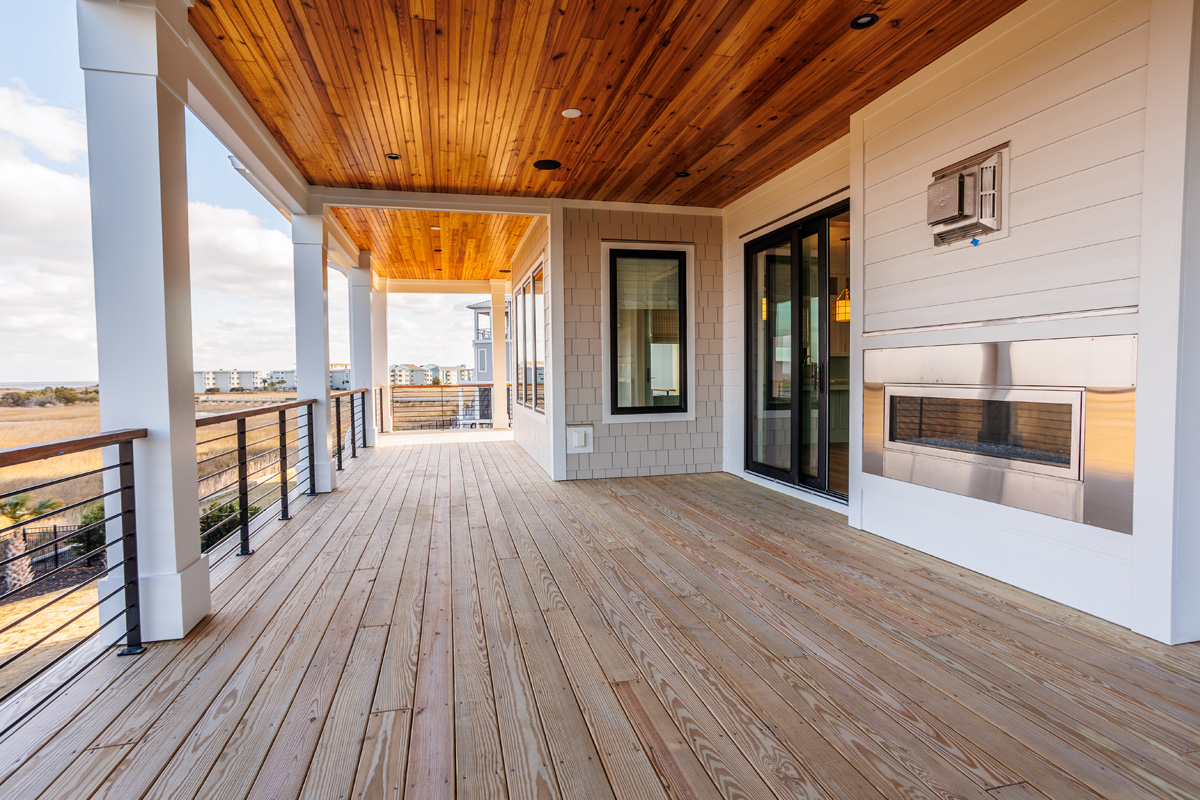 Custom outdoor AV installation by AcoustiCreations featuring weather-resistant flush-mount ceiling speakers on a covered wood porch in coastal Wilmington, NC