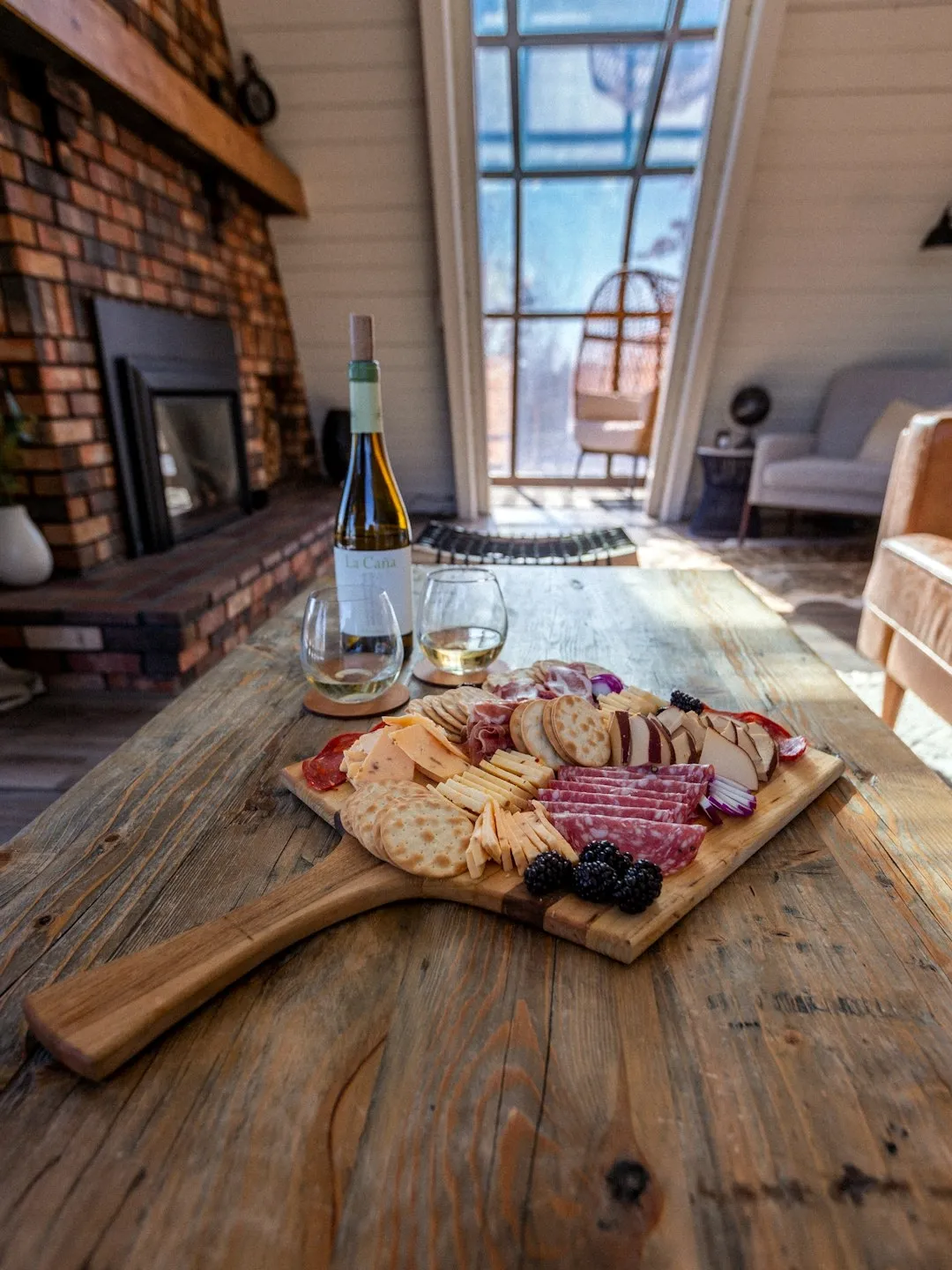 Cozy Portland-area luxury home moment: charcuterie board and wine by a fireplace in warm autumn light