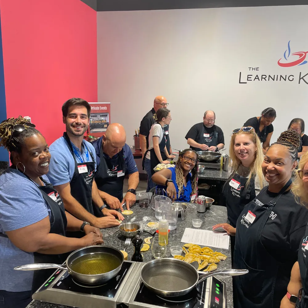 Guests enjoying a hands-on group cooking class at The Learning Kitchen culinary studio during an interactive private event