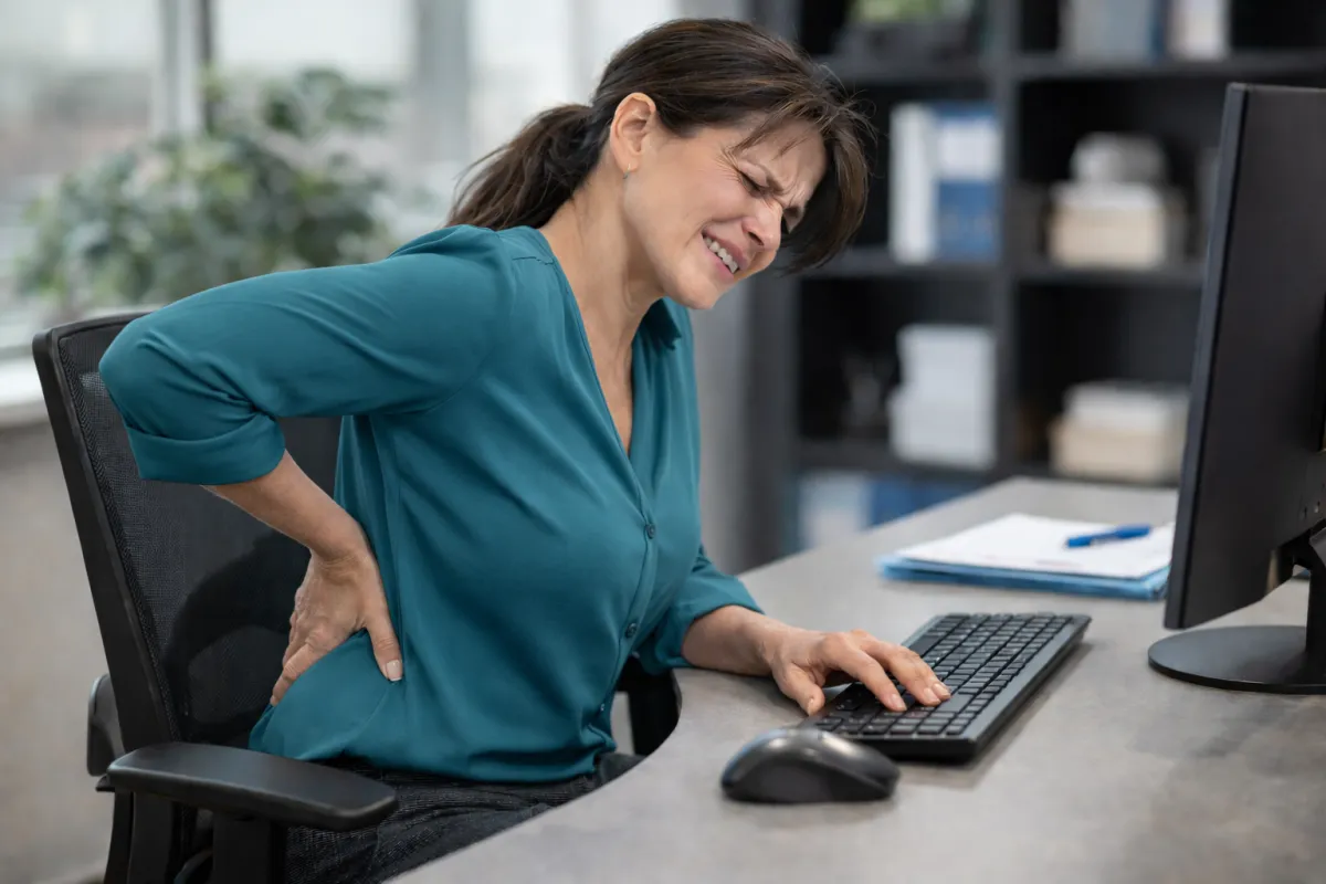 Woman with lower back pain sitting at desk