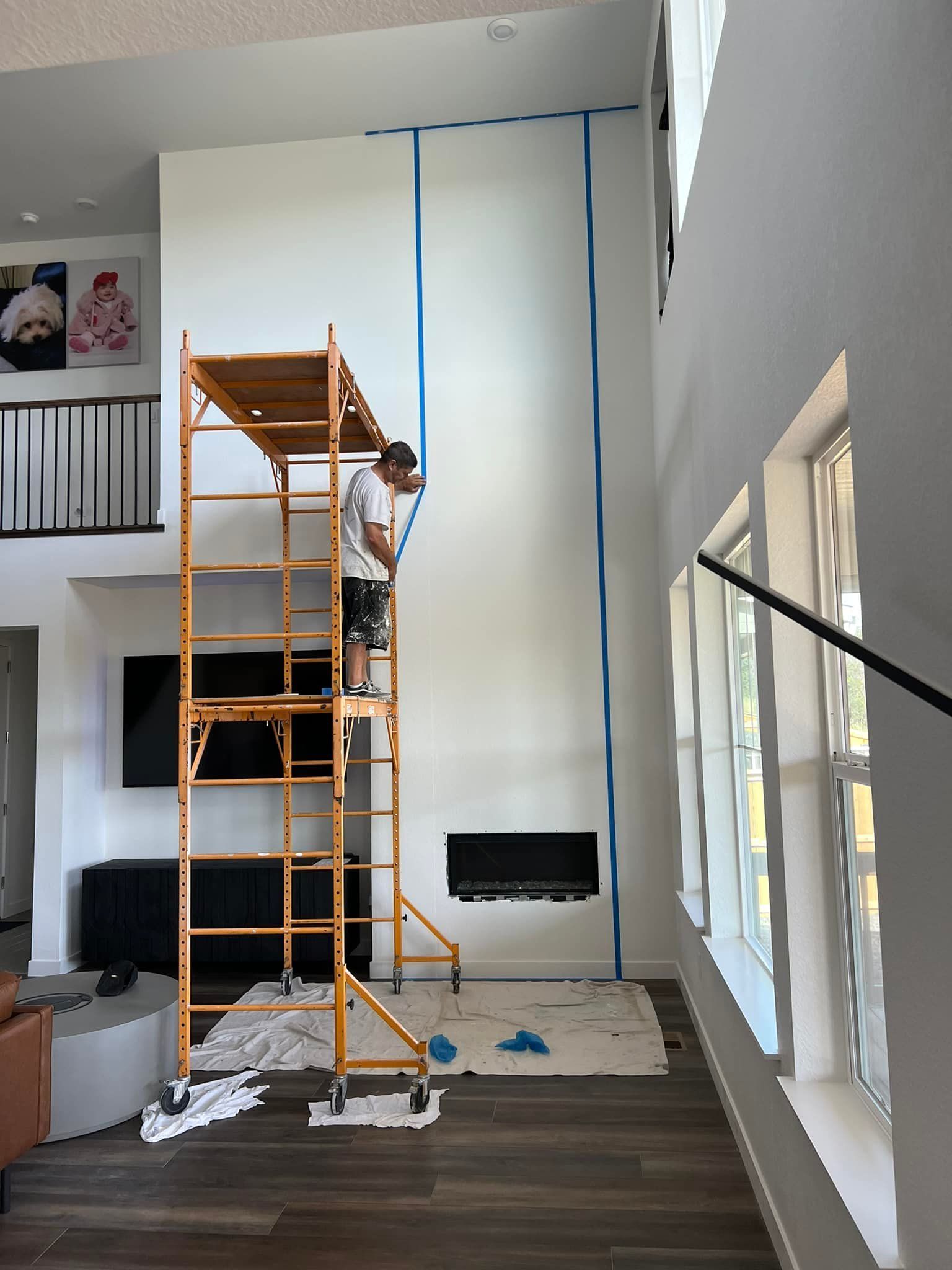 Brightly lit interior of a house featuring a white staircase with black iron railings, white walls, and a hanging chandelier.