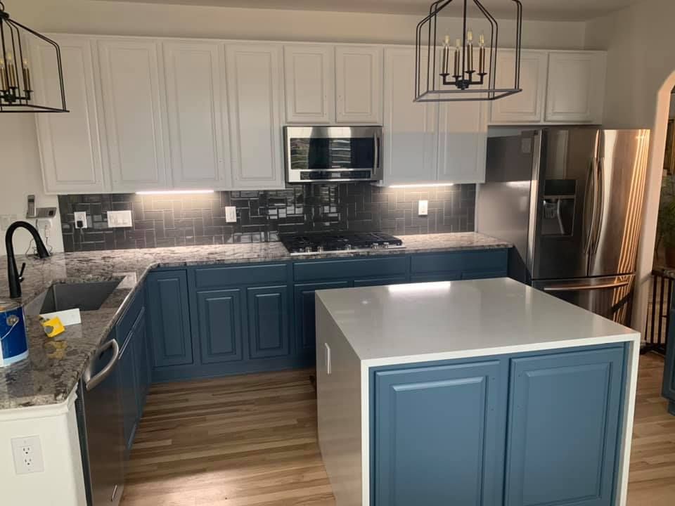A kitchen with white painted cabinets, stainless steel appliances, and a gray countertop