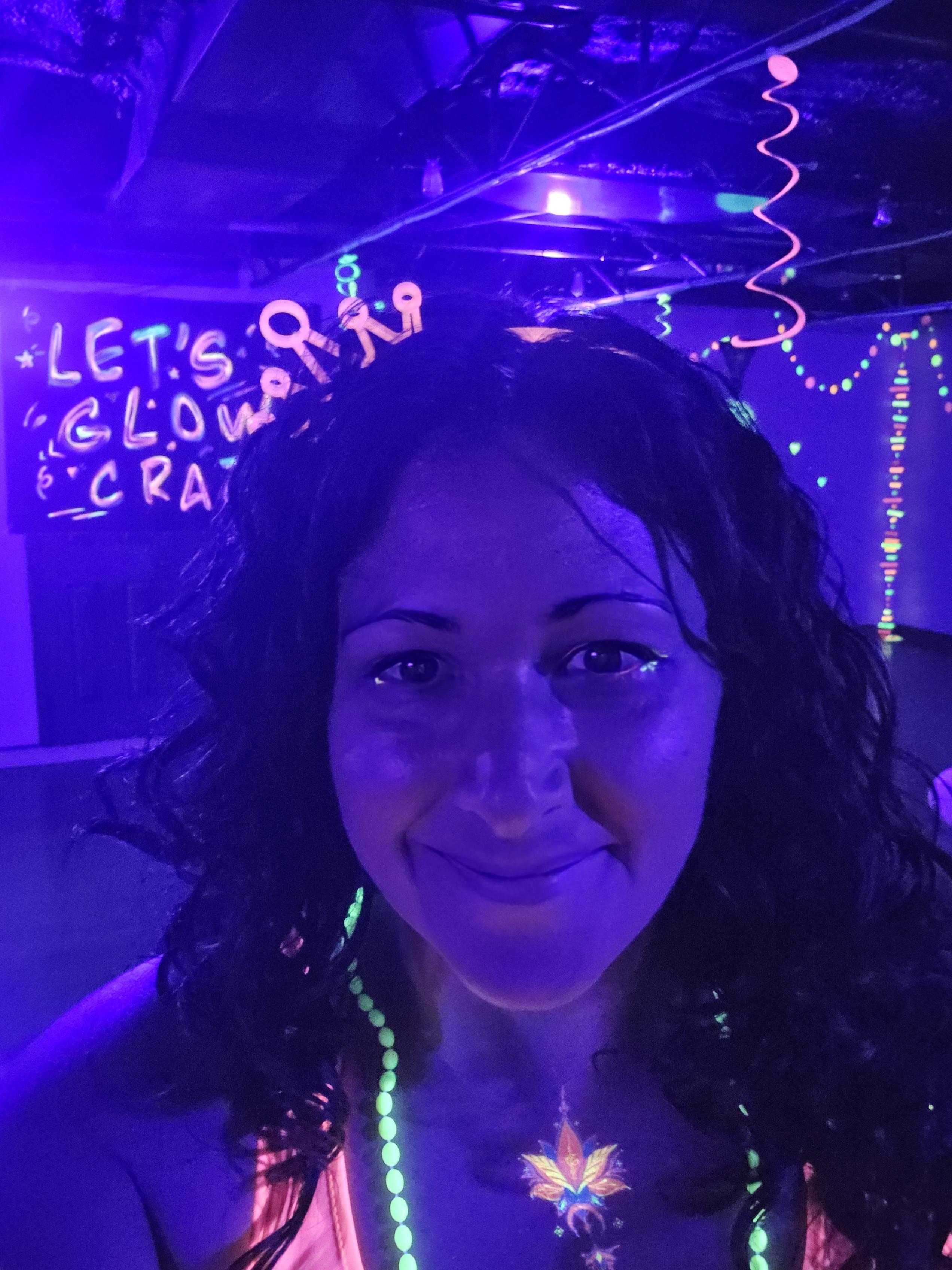 Nicole, yoga instructor smiling in glowing neon activewear and UV body art