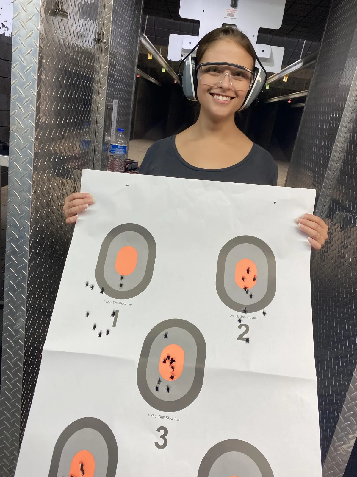 happy female private session student holding up her target at the range