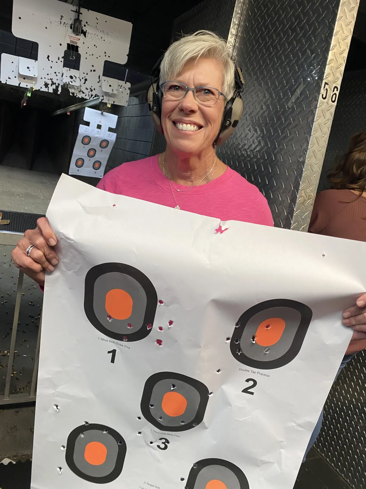 happy female beginners guide to firearms student holding up her target at the range
