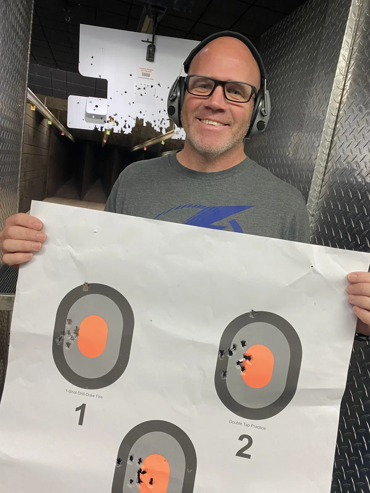 smiling male beginners guide to firearms student holding up his target at the range