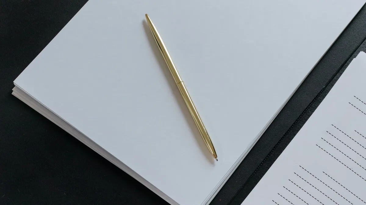 Gold pen on stacks of business documents on a black desk