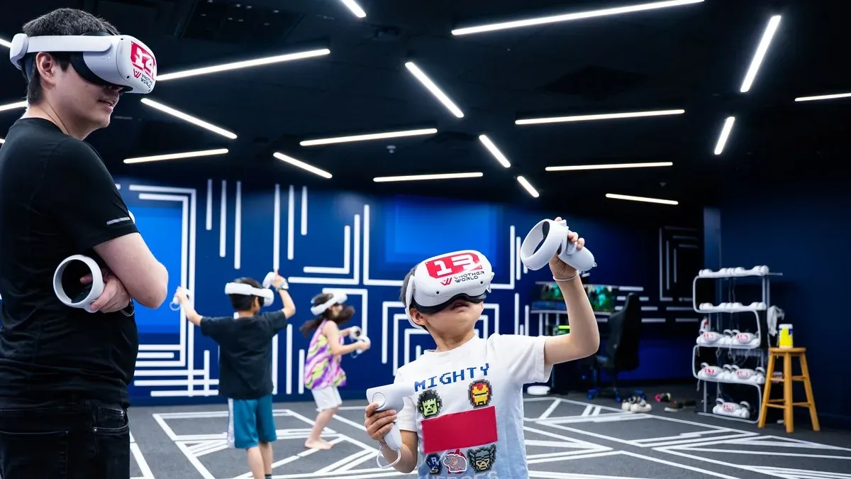 Kids in VR headsets playing together in the free-roam arena at a birthday party at Another World VR in Aldergrove, with a game master watching