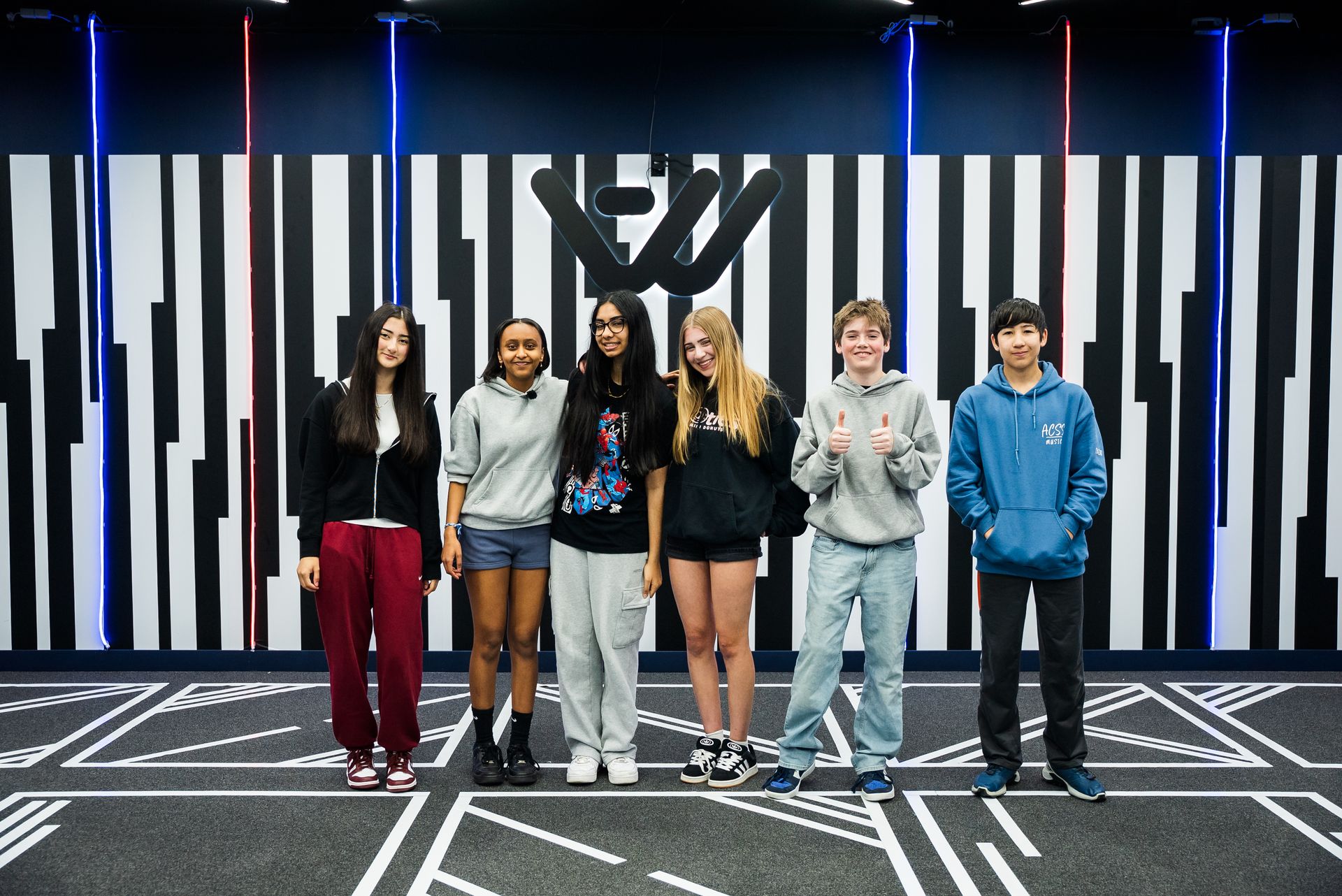 A group of students standing in front of the logo wall