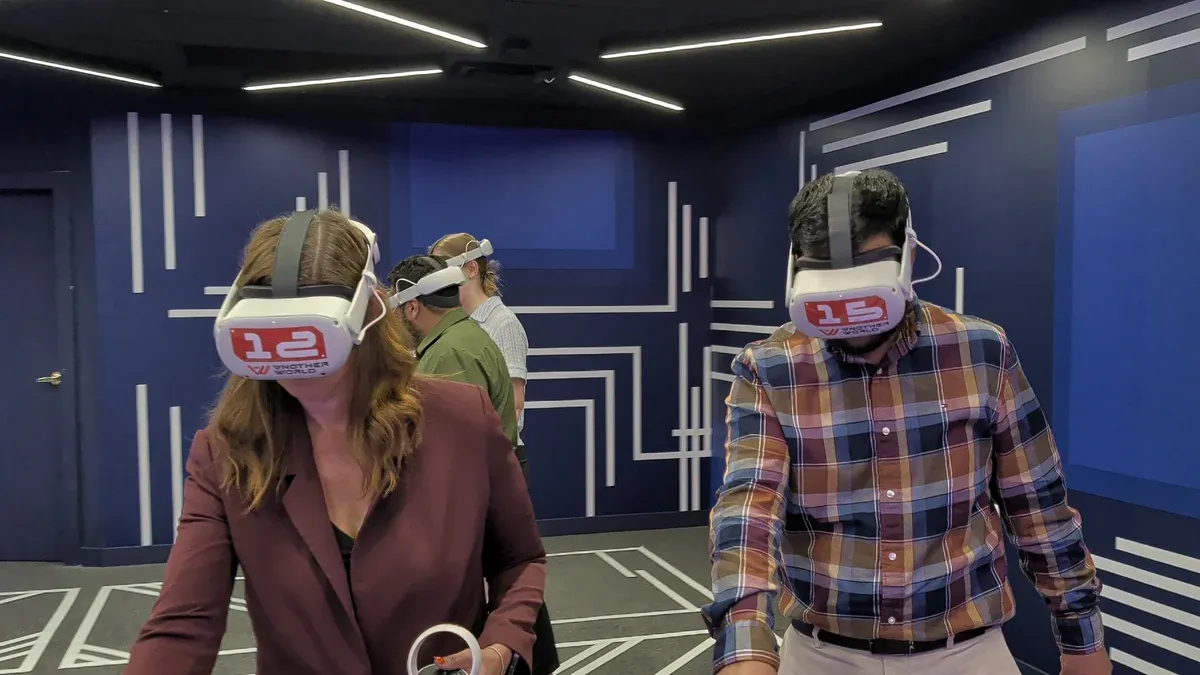 Two adults in VR headsets holding controllers in the free-roam arena at Another World VR in Aldergrove