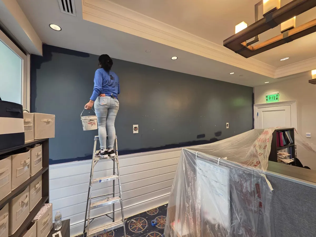 Painter on a ladder painting a navy accent wall at Pelican Isles Yacht Club